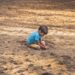 boy playing on sand during daytime
